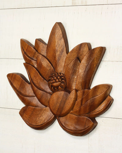 Wooden lotus flower wall decor on a white wooden surface