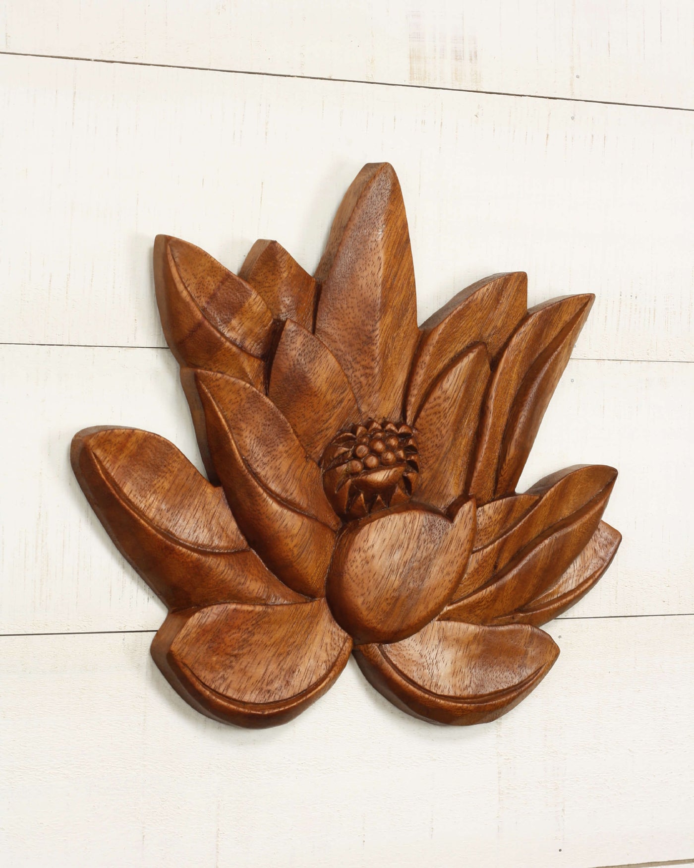 Wooden lotus flower wall decor on a white wooden surface