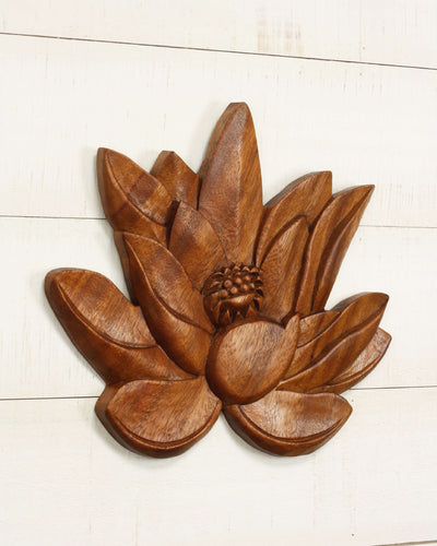 Wooden lotus flower wall decor on a white wooden surface