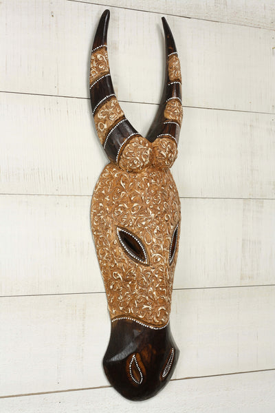 Decorative animal head with intricate patterns on a white wooden background