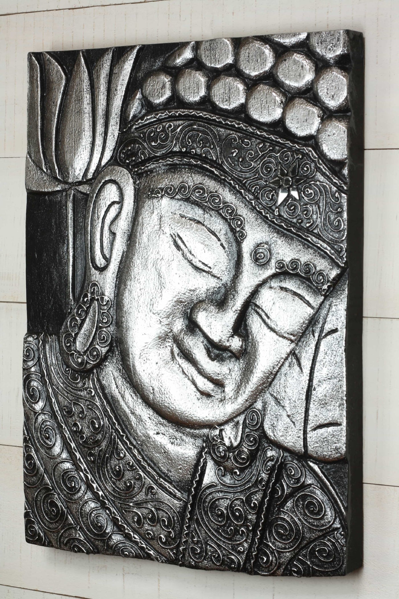 Decorative wall art of a Buddha face with intricate patterns on a black background.