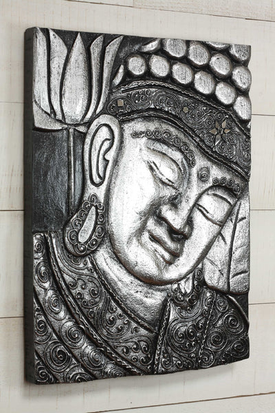 Decorative wall art of a Buddha face with intricate patterns on a light wooden background